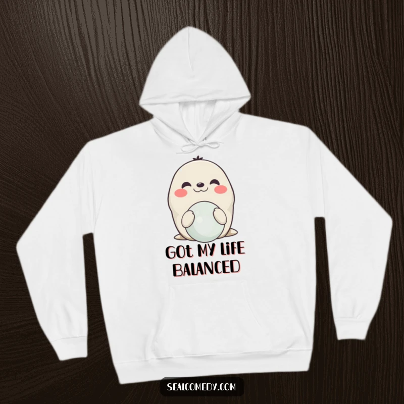Funny smiling seal hoodie, showing a happy seal balancing a ball on its nose, perfect for cozy days and applause.